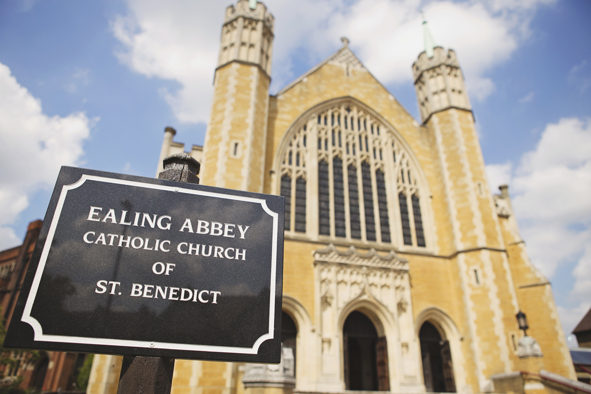 A wide shot of Ealing Abbey with a black sign in the foreground saying Ealing Abbey Catholic Church