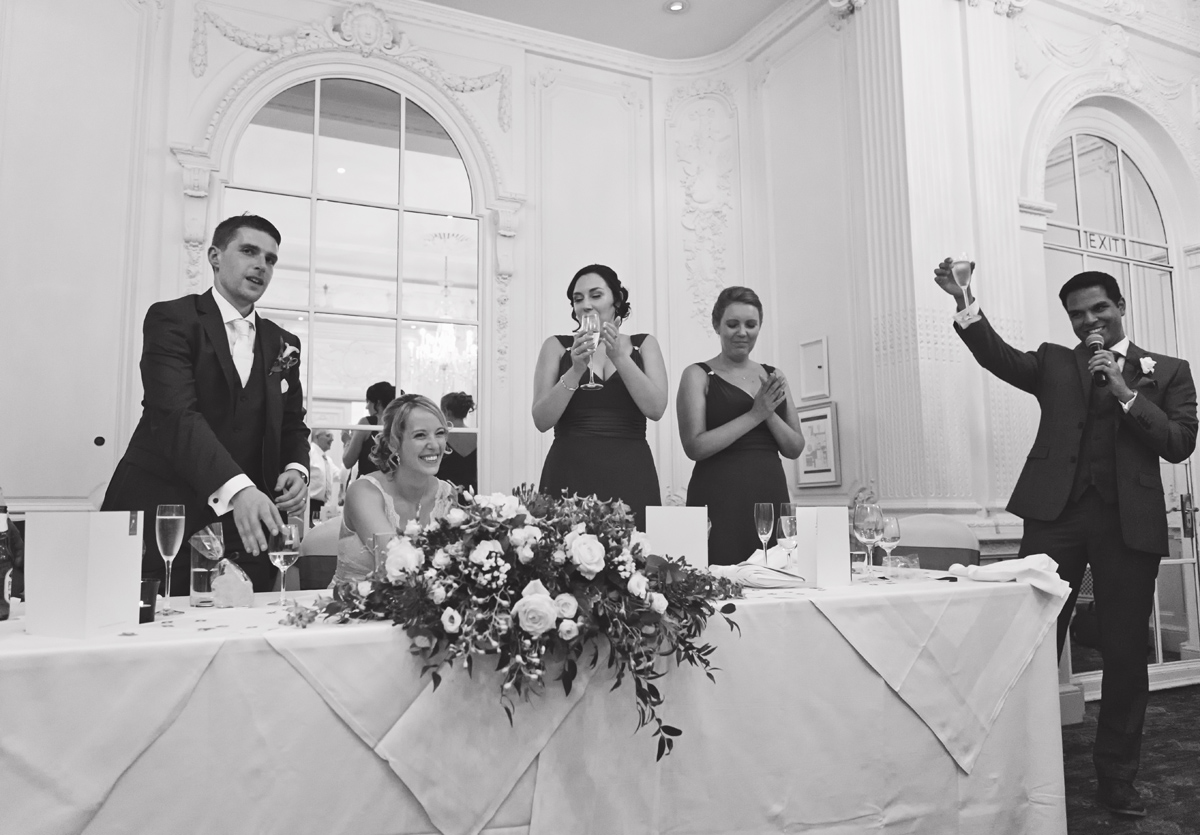 A groomsman toasts the bride and groom along with their bridesmaids at a wedding