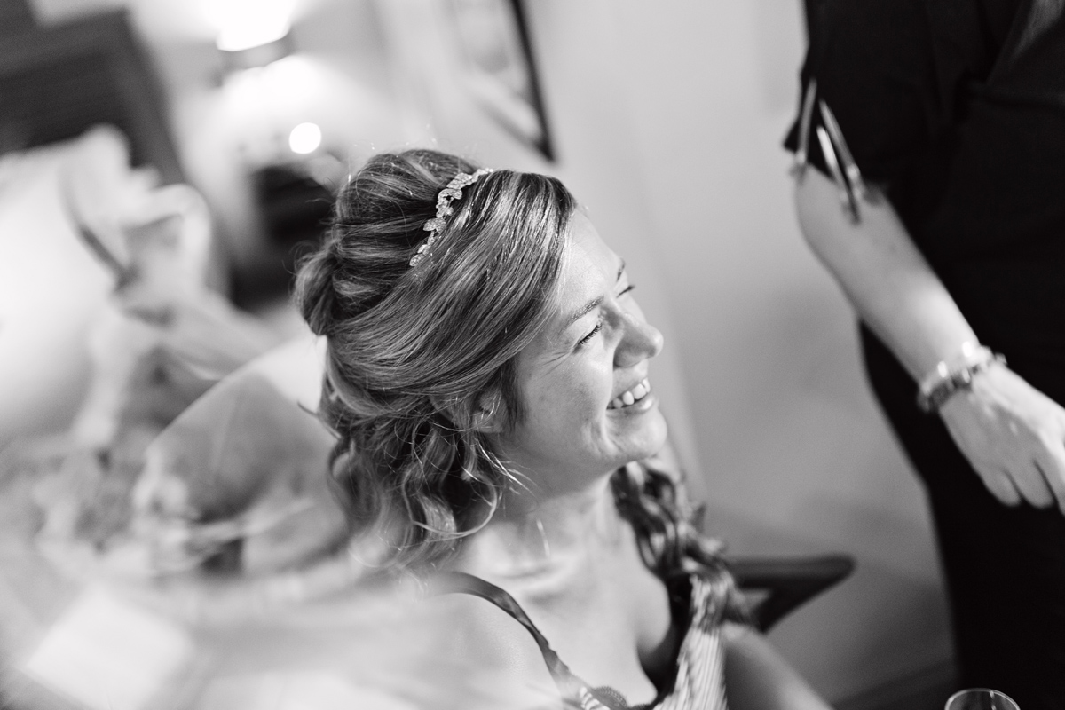 A black & white shot of a bride laughing without makeup on