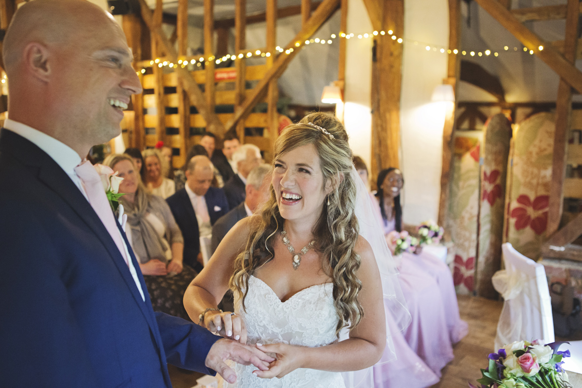 A wedding couple laughing as the bride attempts to put the ring on the Groom's finger
