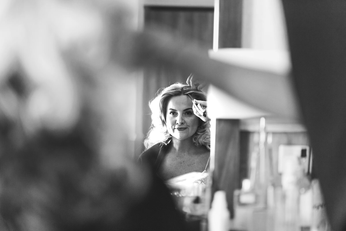 A mono image of a bride looking at her reflection in the mirror