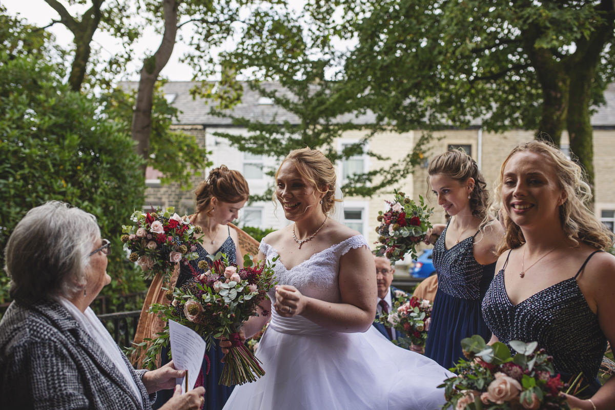 A bride and her bridesmaids arrive outside a church smiling