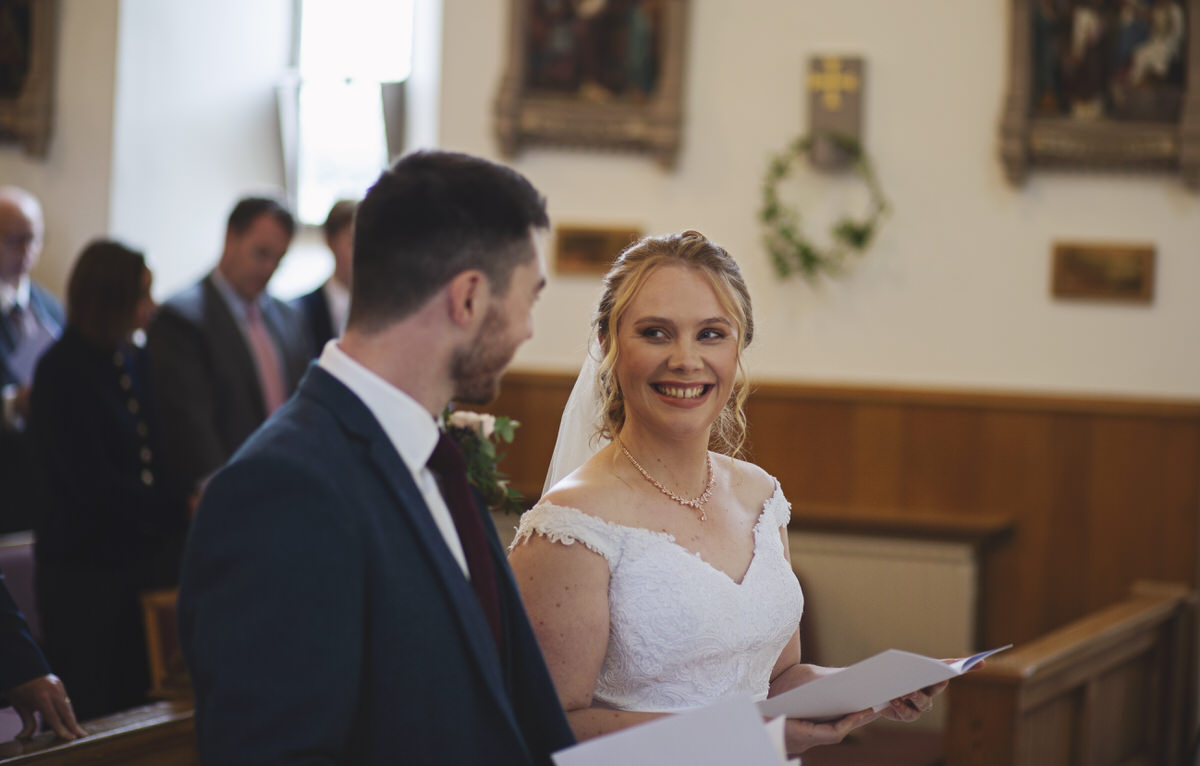 A bride smiles at her groom at the church alter