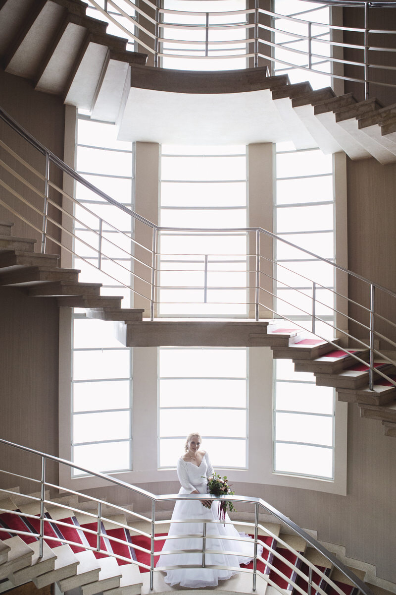 A bride smiles at the camera whole standing on a spiral staircase at The Midland Hotel in Morecambe